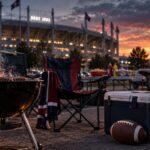 Grill, Klappstühle und Football bei einem symbolischen Tailgate vor einem Stadion